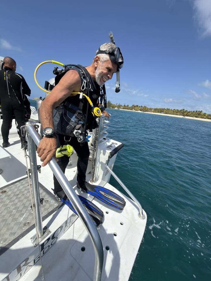 A smiling diver stepping onto the back of the boat, ready to dive