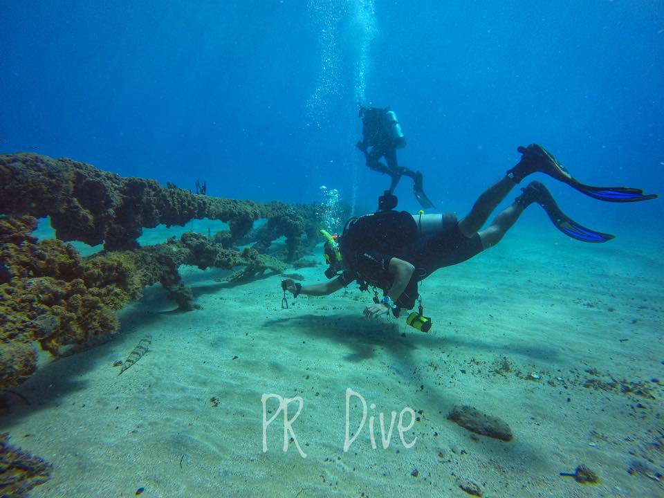 A diver swimming over a wreck on the sand