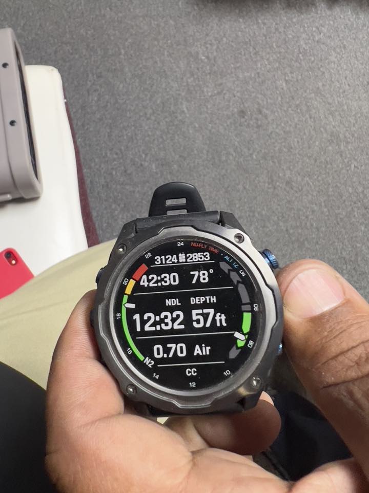 A Garmin dive computer held in hand