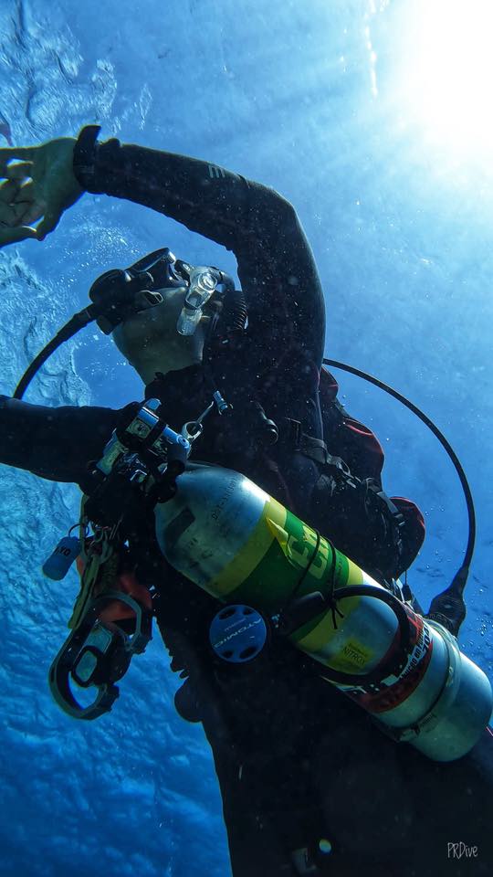 A sidemount diver with a cylinder clipped at the side